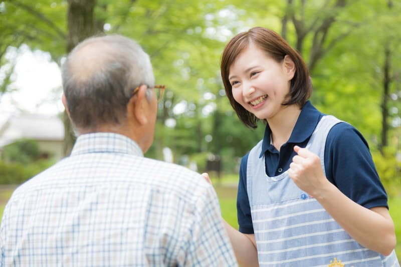 ご利用者の高齢男性と笑顔で言葉を交わす介護スタッフ