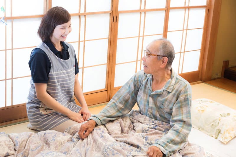 ご自宅の和室で高齢の男性に寄り添う介護スタッフ。毎日の家事と暮らしをやさしく支えます